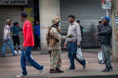 A South African National Defense Forces soldier makes sure the safe distance between people is respected in the commercial area of the Alexandra township of Johannesburg, South Africa, Friday April 3, 2020. South Africa went into a nationwide lockdown for 21 days in an effort to control the spread of the coronavirus. The new coronavirus causes mild or moderate symptoms for most people, but for some, especially older adults and people with existing health problems, it can cause more severe illness or death.(AP Photo/Jerome Delay)