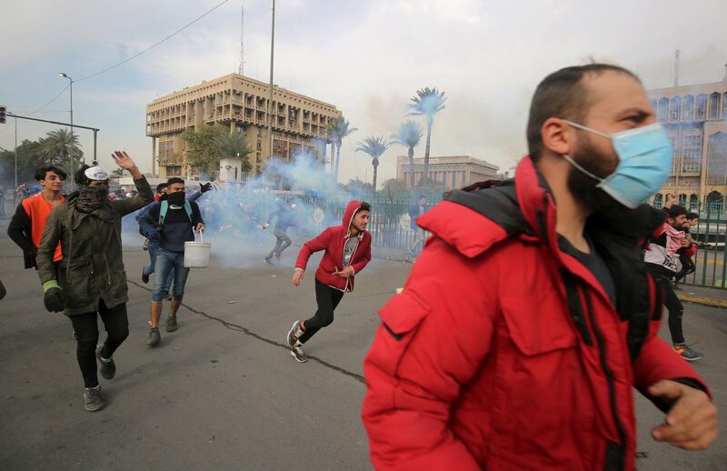 Iraqi protesters run for cover during clashes with riot police following a demonstration in Al-Khilani Square in  the capital Baghdad on January 29, 2020. AFP