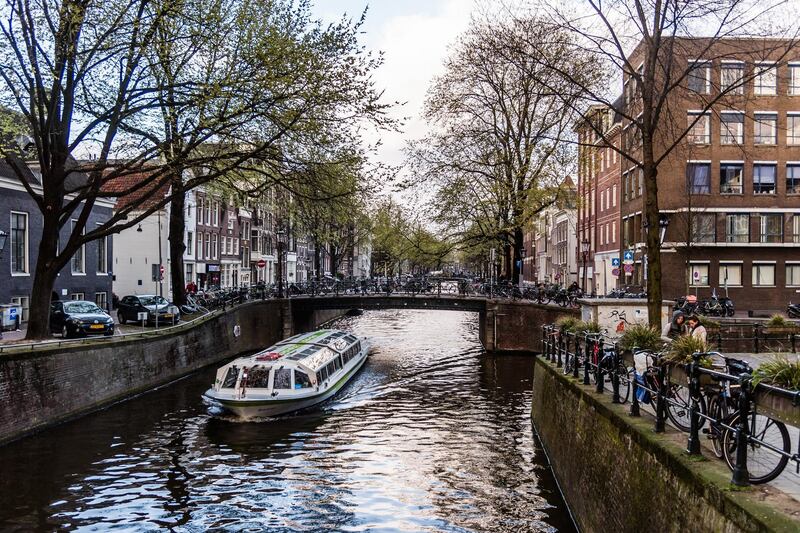 A sightseeing barge travels on a canal in Amsterdam, Netherlands, on Monday, March 25, 2019. Amsterdam is the latest European city to try to get a grip on its buy-to-let housing market as it seeks to stop a wave of landlords from capitalizing on booming property prices. Photographer: Geert Vanden Wijngaert/Bloomberg