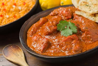 E1A735 A delicious bowl of creamy chicken tikka masala with rice, lemons, and naan bread. Alamy