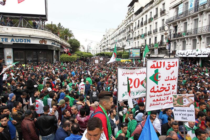 (FILES) A file photo taken on April 19, 2019 shows Algerians, waving national flags and carry anti corruption placards, marching during an anti government demonstration in the capital Algiers. Algeria is readying for a constitutional referendum that the establishment says will usher in a "New Republic" and boost freedoms, but the opposition dismisses it as window-dressing by a repressive regime. With a month to go before the November 1 referendum, many ordinary Algerians -- struggling in a deep economic crisis with soaring unemployment -- appear unaware of the technical details of what the government proposes.
 / AFP / -
