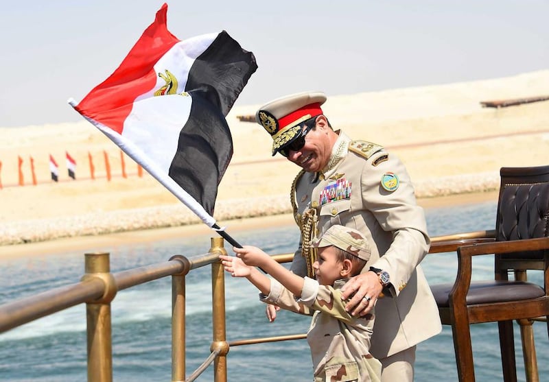 A gift to the nation: Egyptian president Abdel Fattah El Sisi helps a young boy wave the country’s flag from a yacht during the opening ceremony of the new Suez Canal. AFP Photo