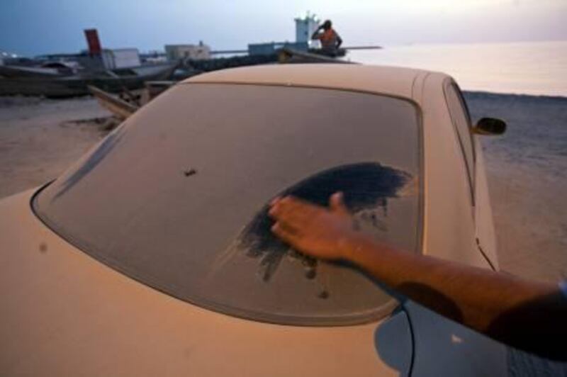 Ras al Khaimah - July 8, 2010 - One week after washing his car, this owner wipes the dust that has settled on it from the car's rear window in the village of Ghalilah, where he lives, about 25 kilometers north of Ras al Khaimah, July 8, 2010. (Photo by Jeff Topping/The National) 
 
