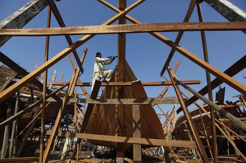 A carpenter uses manual tools to cut out a wood panel while working on a boat at a yard in Karachi's Fish Harbour. Akhtar Soomro / Reuters