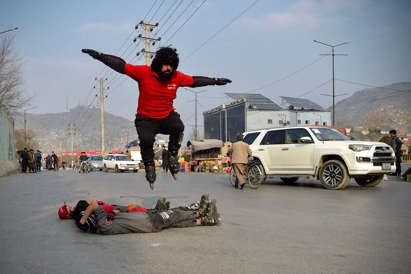 Youths perform stunts on roller-skates, during a car racing competition in Kabul. AFP