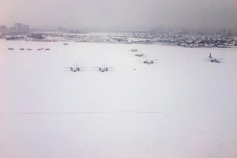 A picture taken through the window of a landing airplane shows snow covered aircrafts on the tarmac of Sofia airport on February 26, 2018.  Dimitar Dilkoff / AFP