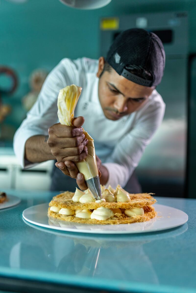 A chef putting the finishing touches on a dessert.