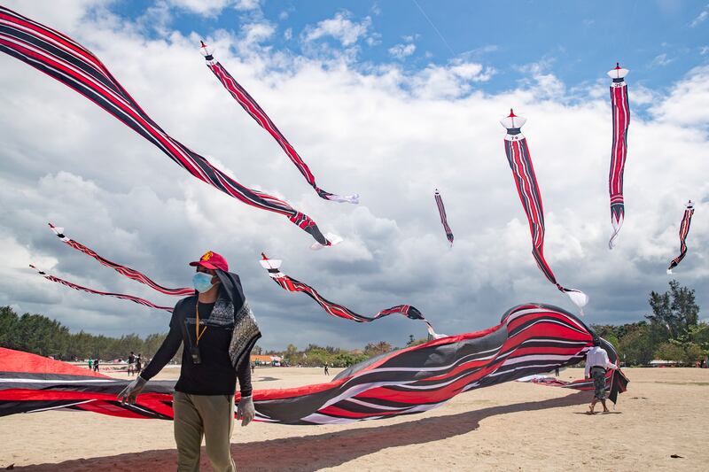 People fly kites during a traditional kite festival in Sanur, Bali, Indonesia, 28 August 2022.  The primary colors used for Balinese kites are black, red, white and gold/yellow, which represent the incarnations of the Hindu deities.  The festival is a popular tourist attraction in Bali.   EPA / MADE NAGI