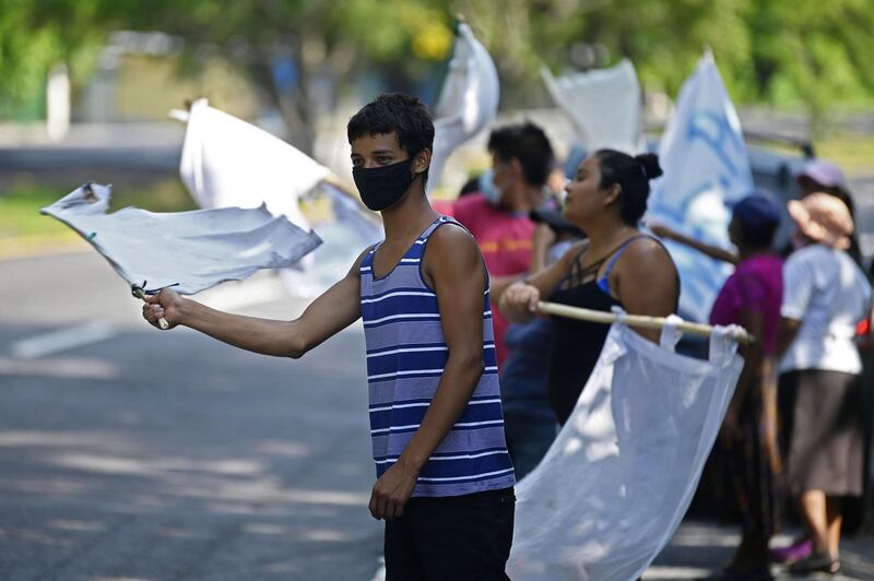 People flutter improvised white flags along a road to show their need for food during a mandatory quarantine imposed by the government against the spread of the new coronavirus in San Pedro Perulapan, El Salvador.  AFP