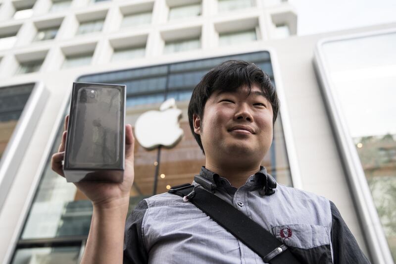 A customer holding an iPhone 11 box poses outside the Apple Marunouchi store in Tokyo. Getty Images