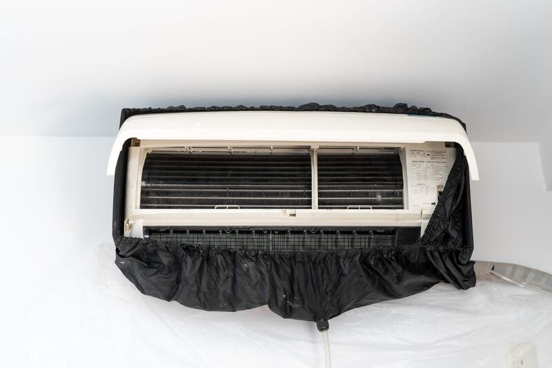 Man Cleaning Air Conditioner At Home. Getty Images