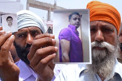 Wassan Singh (L) and Gurdiyal Singh, the respective fathers of Kuljeet Singh and Jasbir Singh, pose at the Golden Temple with portraits of their sons in Amritsar on June 19, 2014, after news that their children were among 40 Indian workers taken hostage in Iraq. India's new government struggled June 18 to make headway in its first foreign crisis as it tried to secure the release of 40 construction workers being held in war-torn Iraq, home to some 10,000 Indian expatriates. AFP PHOTO/NARINDER NANU / AFP PHOTO / NARINDER NANU