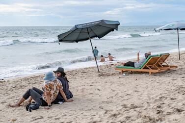 Tourists sit at a beach in Kuta, Bali, Indonesia, 29 December 2021.  The Indonesian government cancelled the plan of Level 3 restrictions on community activities (PPKM) which was intended to be imposed during Christmas and New Year's holidays.   EPA / MADE NAGI