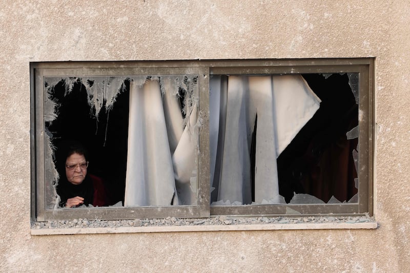 A woman looks out from her damaged building. AFP
