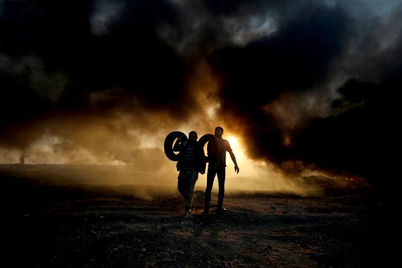 Palestinian protesters carry tyres as smoke billows at the Israel-Gaza border, east of Gaza city. AFP