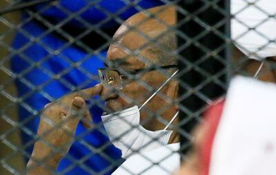 Sudan's ousted president Omar Al Bashir sits inside a courtroom cage during his trial over the 1989 military coup that brought him power. Reuters
