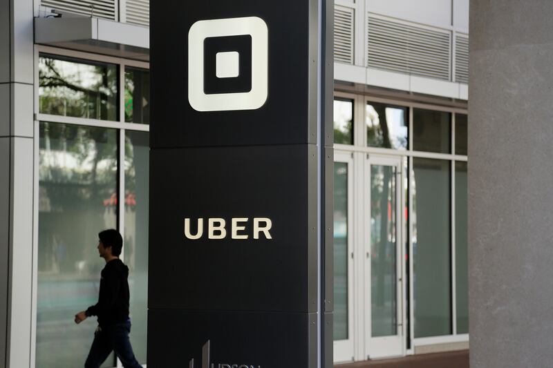 FILE - In this June 21, 2017, file photo a man walks into the building that houses the headquarters of Uber in San Francisco. Uber and at least five other major California companies are scheduled to go public this year, and when it happens it will produce a tax windfall for state government. (AP Photo/Eric Risberg,File)