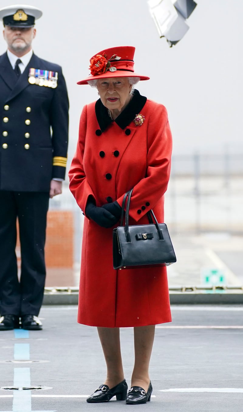 Queen Elizabeth II, wearing red, during a visit to HMS Queen Elizabeth at HM Naval Base ahead of the ship's maiden deployment on May 22, 2021 in Portsmouth, England. Getty Images