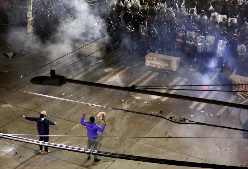 Two protesters hold their ground with their hands up as police deploy chemical agents and blast balls during a protest in Seattle, Washington. REUTERS