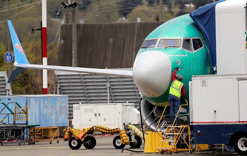 A worker stands near the nose cone of a Boeing 737 Max 8 jet, built for China Southern Airlines, parked at a Boeing Co. production facility, Monday, April 8, 2019, in Renton, Wash. Boeing said the week before that it will cut production of its troubled 737 Max airliner in April, underscoring the growing financial risk it faces the longer that its best-selling plane remains grounded after two crashes. (AP Photo/Elaine Thompson)