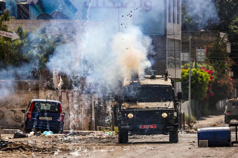 Israeli soldiers fire tear gas canisters from an armoured vehicle during a military operation in the occupied West Bank city of Jenin on July 4, 2023.  AFP