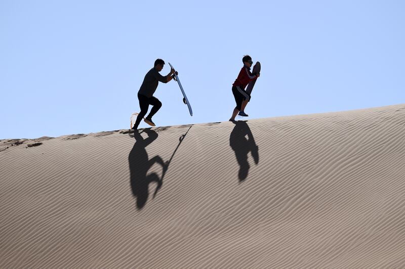 Chinese visitors use skateboards on a sand dune in Al Ain. AFP