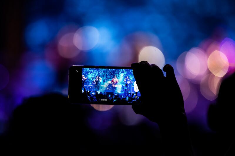 A fan records a video as Boney M featuring Maizie Williams perform.