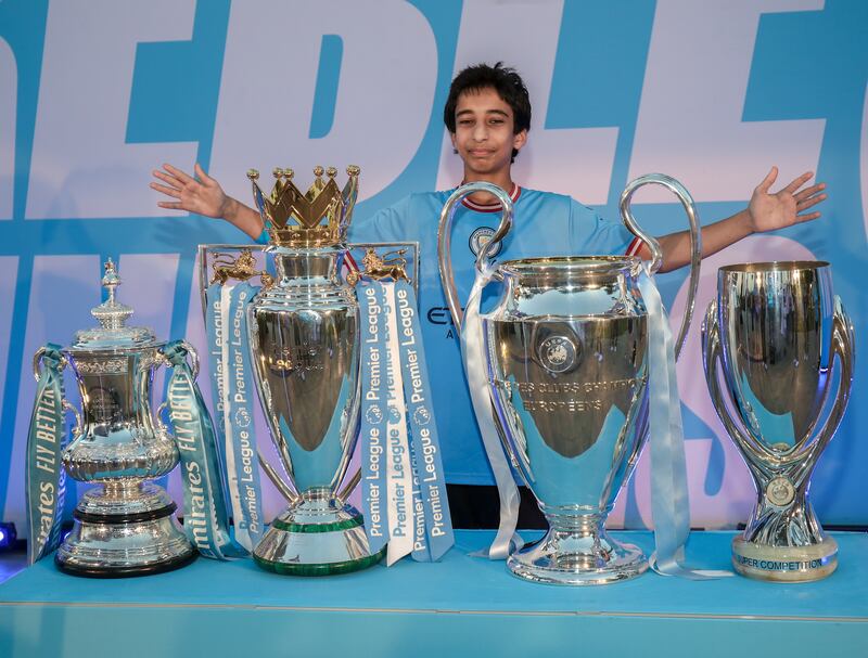 A Manchester City fan poses with the club's trophies at the Louvre Abu Dhabi