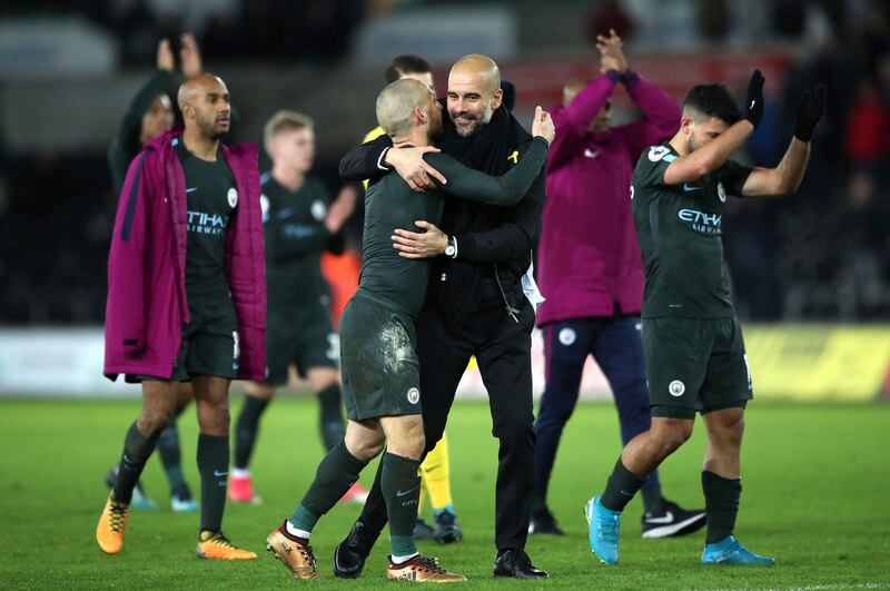 Manchester City manager Pep Guardiola, centre right, and David Silva celebrate their victory after the final whistle of the game against Swansea City, during their English Premier League soccer match at the Liberty Stadium in Swansea, England, Wednesday Dec. 13, 2017. (Nick Potts/PA via AP)