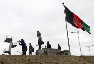 Youths take pictures next to an Afghan flag on a hilltop overlooking Kabul, Afghanistan, April 15, 2021. REUTERS/Mohammad Ismail