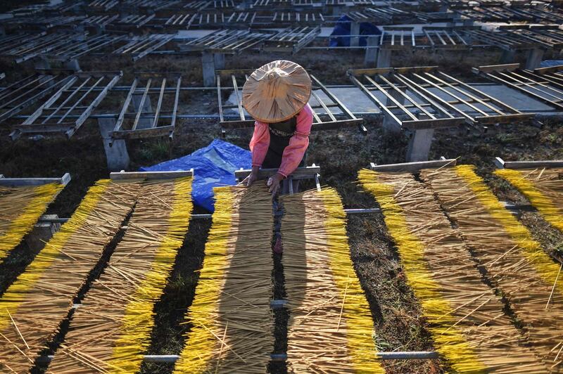 A worker places incense sticks on a wooden platform to dry at the Fujian Xingquan Incense Factory in the city of Quanzhou in China's Fujian Province. AFP