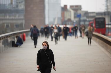 A woman wearing a protective face mask walks over London Bridge during morning rush hour, amid the coronavirus disease outbreak, in London, Britain, April 1, 2021. Reuters