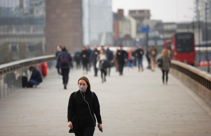 A woman wearing a protective face mask walks over London Bridge during morning rush hour, amid the coronavirus disease (COVID-19) outbreak, in London, Britain, April 1, 2021. REUTERS/Henry Nicholls