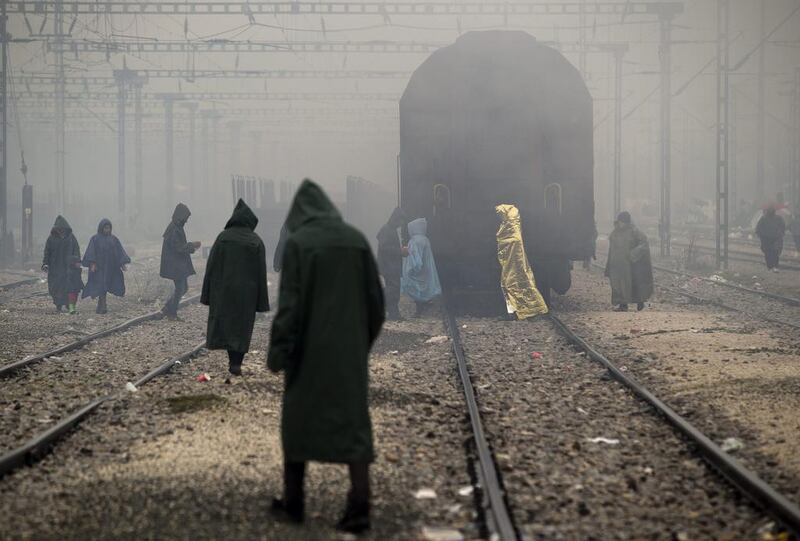 Migrants, one wearing a thermal blanket, walk on railway tracks at the northern Greek border station of Idomeni. Bad weather returned after a brief pause and conditions in the refugee camp on the Greek-Macedonian where about 14,000 people are stranded have further deteriorated. Vadim Ghirda / AP