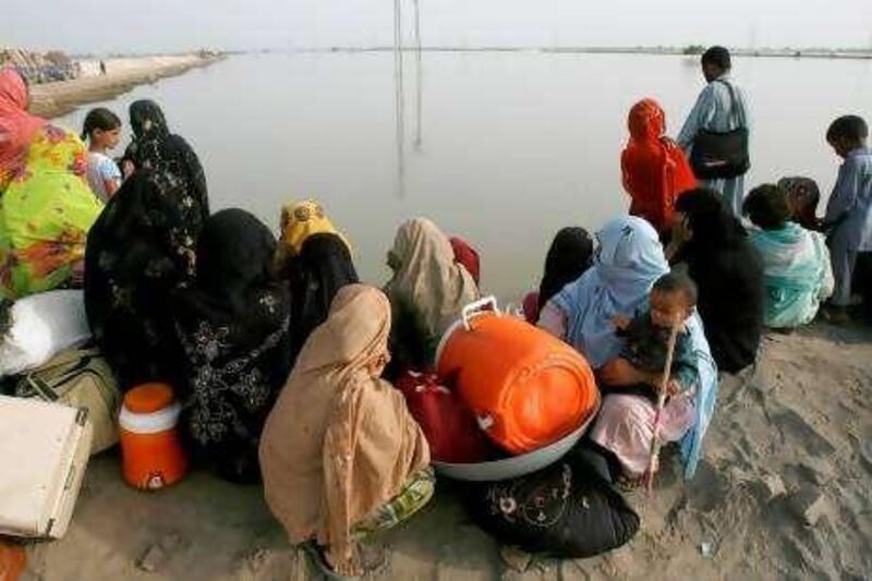 Women and children who are victims of the flood wait for boats at Shikarpur to cross toward their village in Jacobabad, about 78 km (40 miles) from Sukkur in Pakistan's Sindh province August 28, 2010. Flood waters threatened to engulf two towns in southern Pakistan on Saturday, a month after the disaster began, as the United Nations warned that tens of thousands of children risked death from malnutrition. REUTERS/Athar Hussain (PAKISTAN - Tags: DISASTER ENVIRONMENT) TRANSPORT) *** Local Caption ***  SUK03_PAKISTAN-FLOO_0828_11.JPG