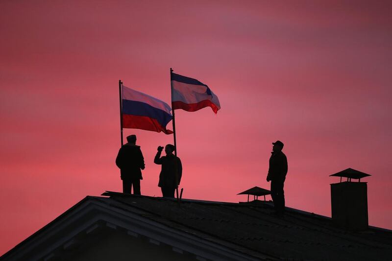 Cossack men install a Russian flag and a Crimean flag on the roof of the City Hall building in Bakhchysarai, Ukraine. Dan Kitwood / Getty