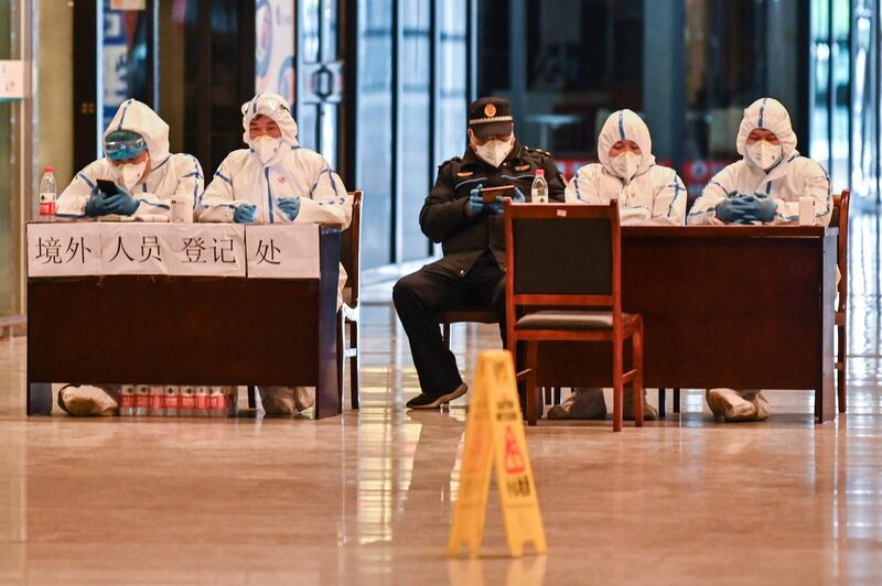 Workers in protective gear wait for passengers arriving at the railway station in Wuhan, China's central Hubei province after travel restrictions into the city were eased following two months of lockdown.  AFP