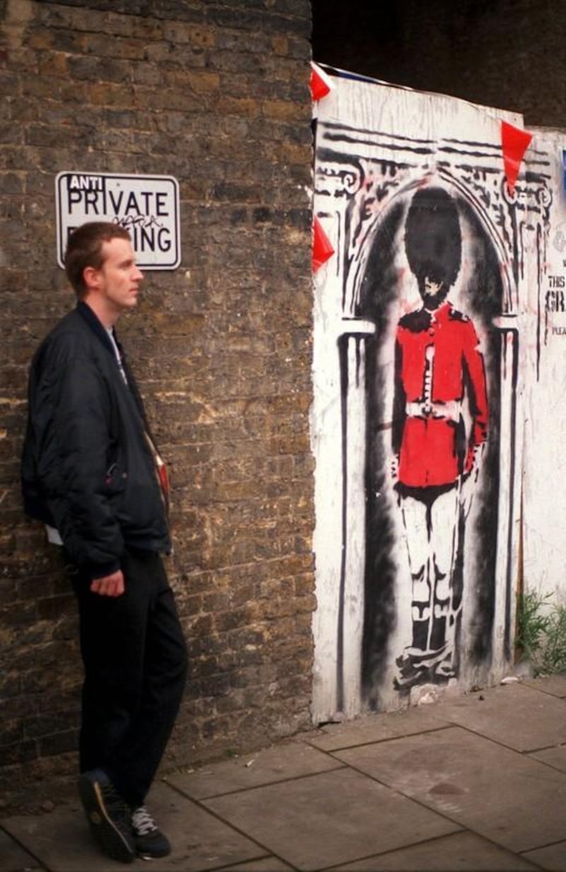 LON01 - 20020531 - LONDON, UNITED KINGDOM : People take a look at a painting by Banksy, one of London's foremost street artists, to celebrate the Queen's Jubilee 30 May 2002, in Clink street, near London Bridge. Banksy, a  graffiti artist uses the streets as his gallery to put across his views in an original way. 
EPA PHOTO EPA / BEN FATHERS
