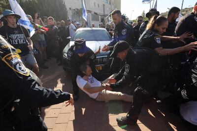 Protesters are removed by police after attempting to block Justice Minister Yariv Levin from leaving his home. AFP