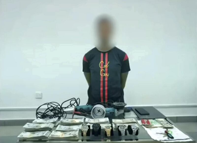 The suspect with some of the stolen cash and goods. Courtesy: Dubai Police