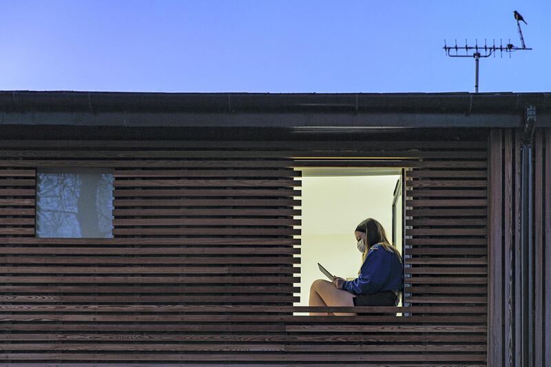 Teenage girl wearing mask sits at her window as study reveals UK's young people are experiencing higher levels of lockdown loneliness than its old. AFP