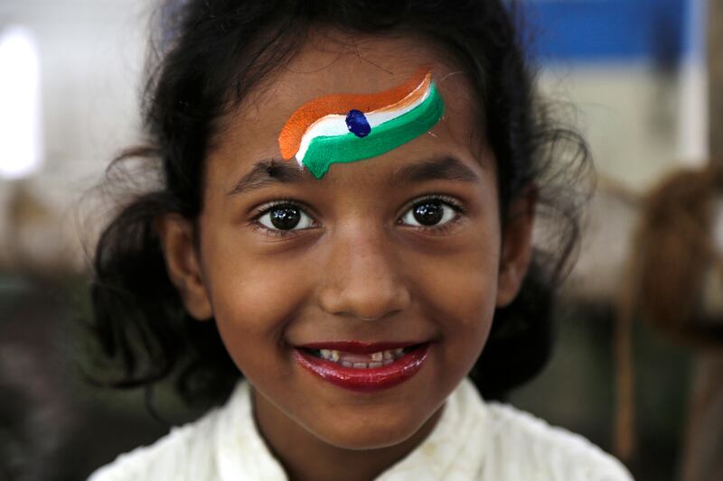 An Indian girl who has colors of the Indian flag painted on forehead smiles to camera near the venue of Independence Day parade in Kolkata, India, Tuesday, Aug. 15, 2017. India commemorated its Independence in 1947 from British colonial rule, on Tuesday. (AP Photo/Bikas Das)