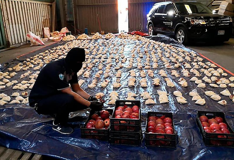 In this photo released by Saudi Press Agency, a Saudi custom officer opens imported pomegranates, as customs foiled a attempt to smuggle millions of Captagon pills, which they said where coming from Lebanon, at Jiddah Islamic Port, Saudi Arabia, Friday, April 23, 2021. Saudi Arabia will ban Lebanese fruits and vegetables entering the kingdom or passing through it because those shipments have been increasingly used to smuggle drugs, the official news agency reported Friday. (Saudi Press Agency via AP)
