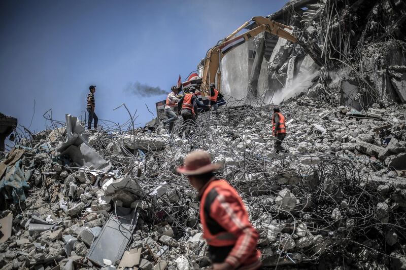 Workers collect the rubble of buildings destroyed during the May rocket attacks. Sanad Latefa for The National
