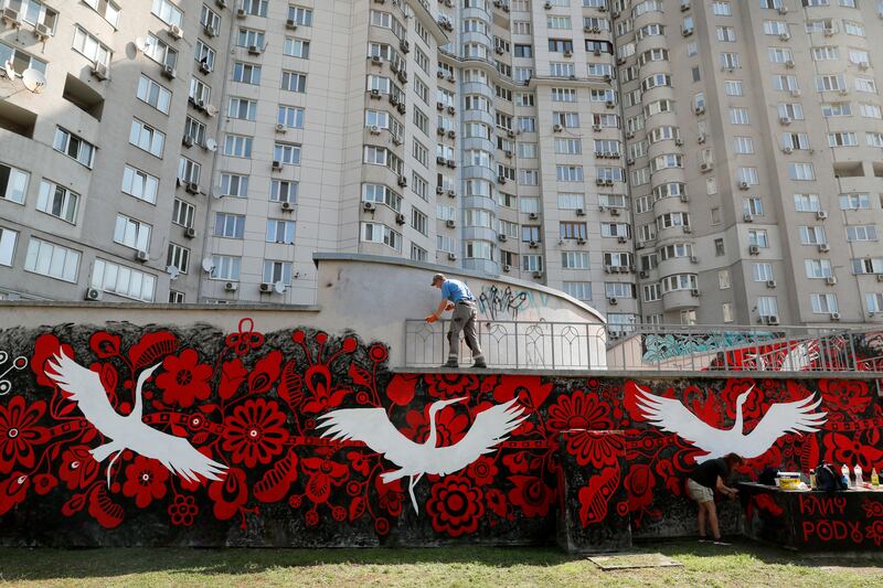 Street artists paint a mural on to a wall near a building in a residential area in Kyiv, Ukraine. EPA