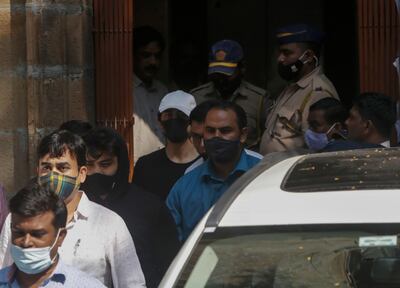 Bollywood actor Shah Rukh Khan’s son Aryan Khan, white cap, and others are escorted by law enforcement officials outside the Narcotics Control Bureau to appear before a court in Mumbai. AP