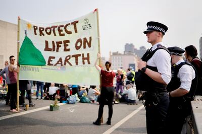 Police look on at climate change activists blockading Waterloo bridge on the third day of an environmental protest by the Extinction Rebellion group, in London on April 17, 2019.  / AFP / Tolga Akmen

