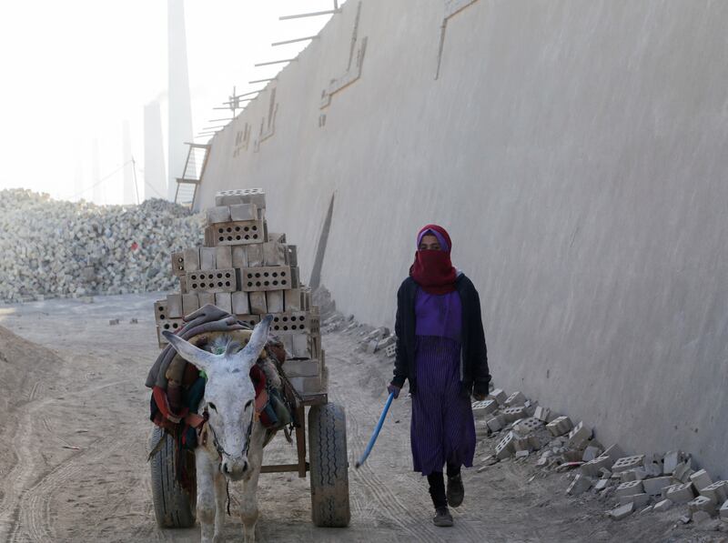 A girl working at the factory with a donkey-drawn cart of bricks.