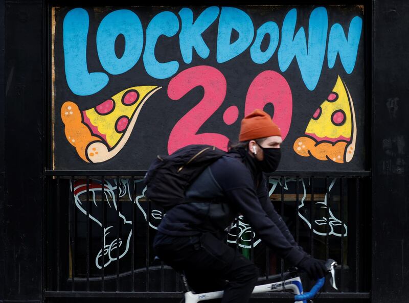 A man cycles past a mural on the boarded up window of a closed pizza restaurant in Manchester. Reuters