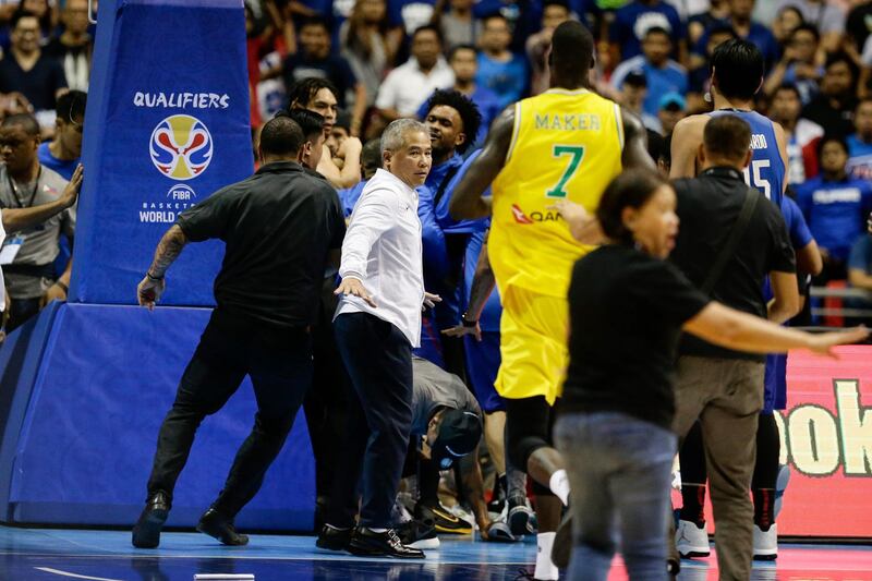 Head coach of the Philippines, Vincent Reyes , centre, attempts to subdue the brawl. Mark R. Cristino / EPA